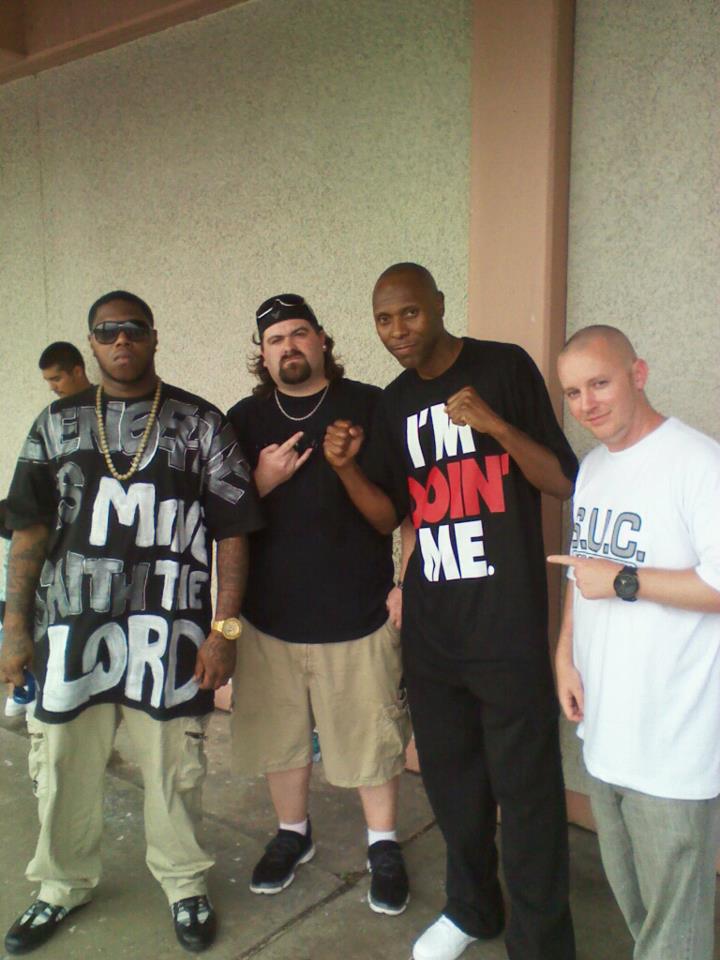 DJ Wrekk posing outside with three friends, one wearing a Screwed Up Click 'S.U.C.' shirt.